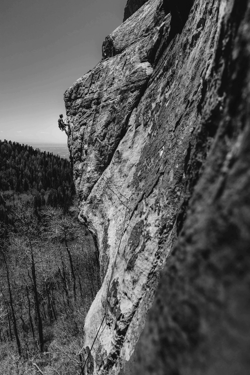 A climber scaling a steep rock face, representing leadership, growth challenges, and overcoming obstacles in marketing and business.