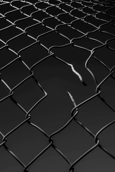 A chain-link fence with a broken section, representing vulnerabilities or overcoming barriers.