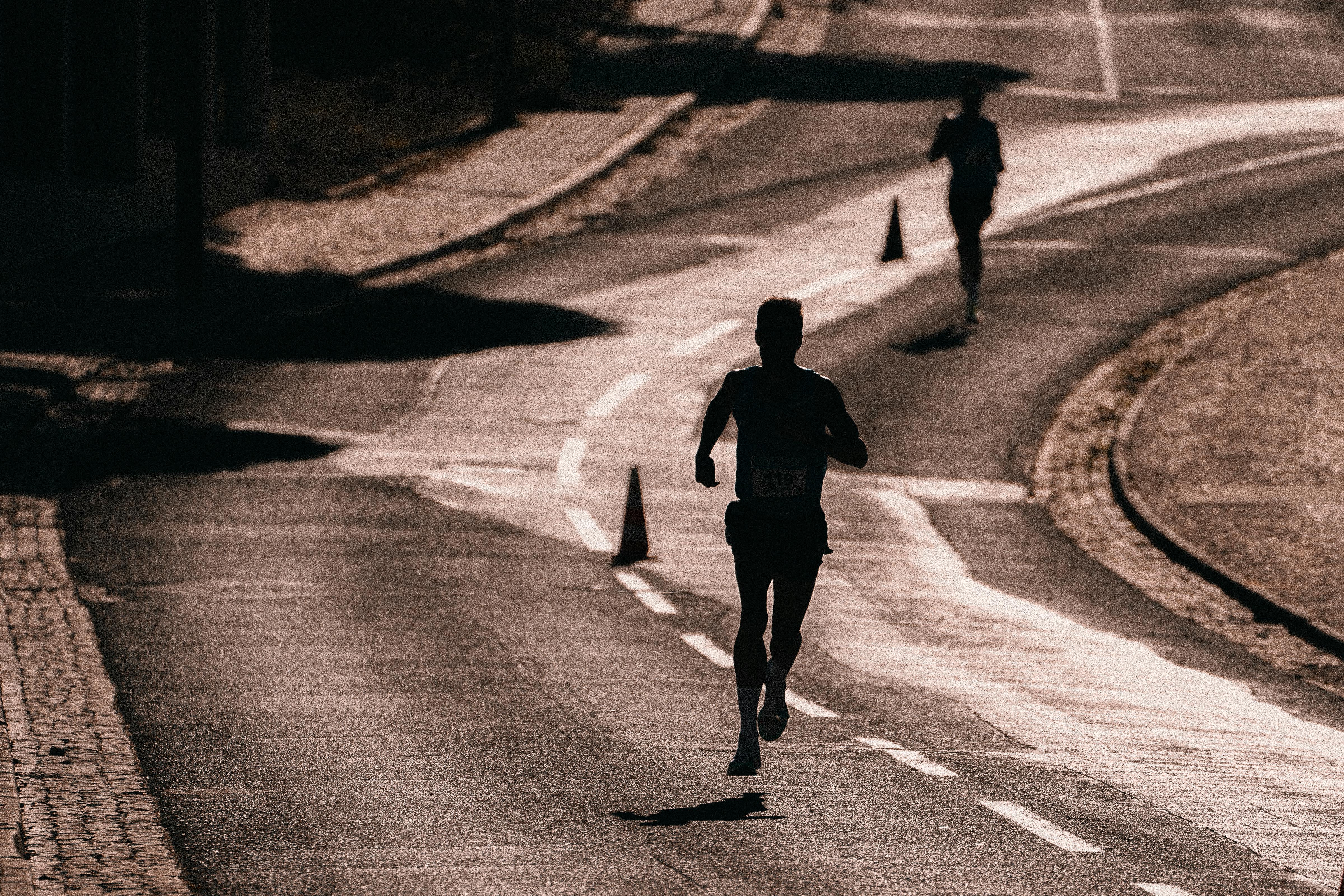 A silhouette of a runner on a sunlit road, symbolizing speed, agility, and progress, with cones marking the path ahead.